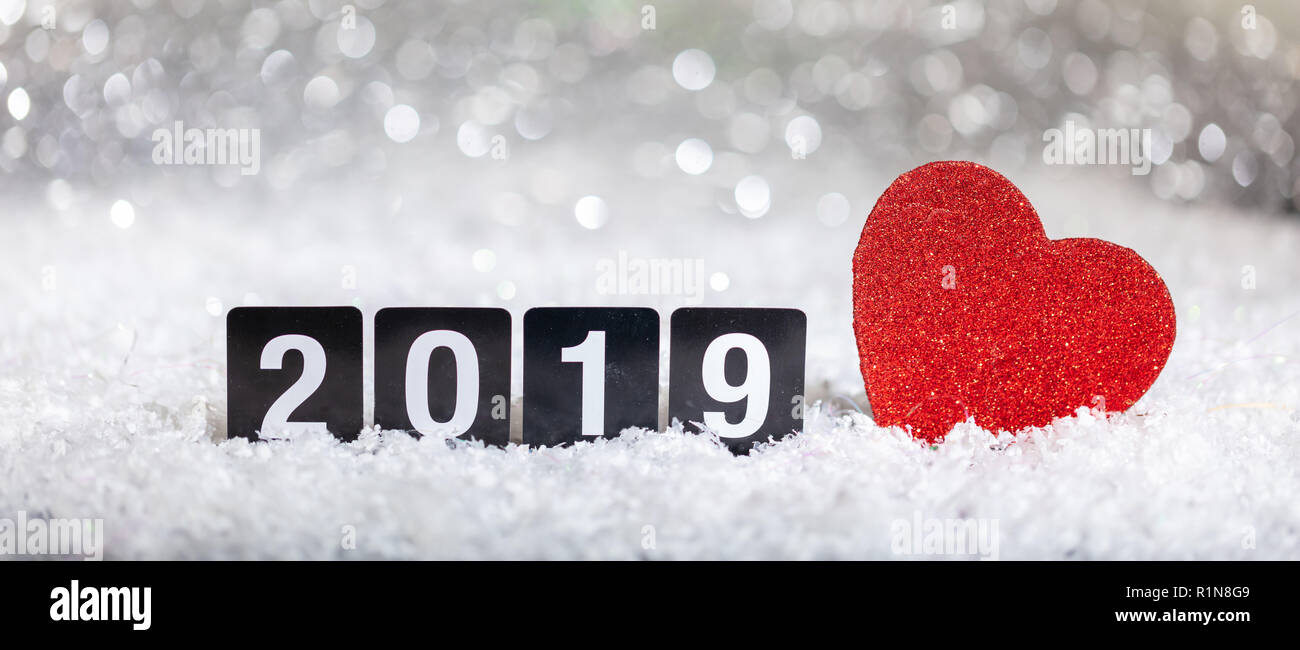 Nouvelle année 2019 et un cœur rouge sur la neige, lumières fond flou d'abstrait. Banque D'Images