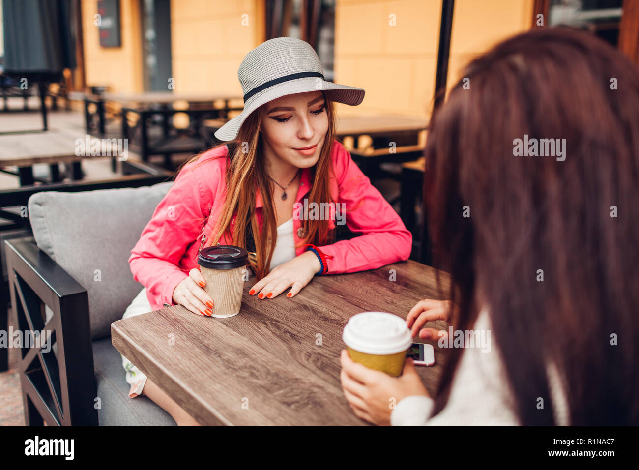 Deux femmes discutant tout en ayant dans café café en plein air. Heureux les amis à l'aide de la vérification téléphonique photos. Pour passer le temps et avoir du plaisir Banque D'Images