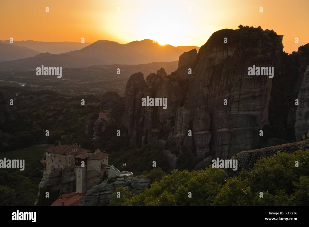 D'énormes rochers de monastères et le coucher du soleil derrière les montagnes lointaines de météores, Thessalie, Grèce Banque D'Images