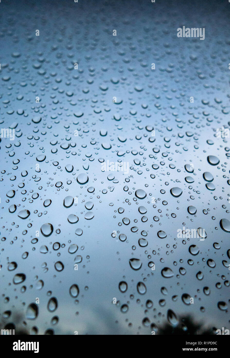 Gouttes de pluie sur fenêtre contre ciel sombre sombre Banque D'Images