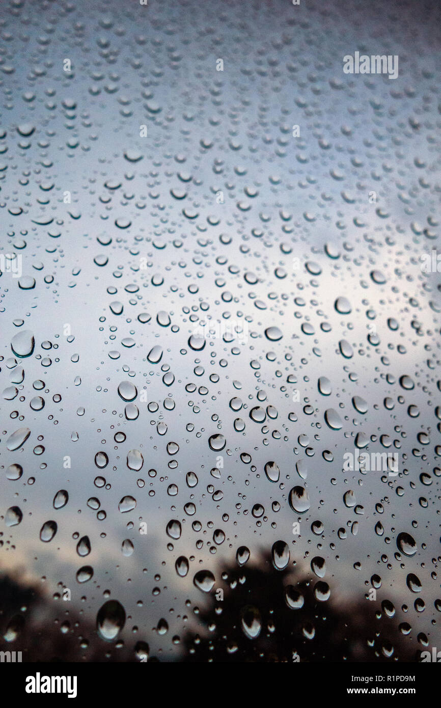 Gouttes de pluie sur fenêtre contre ciel sombre sombre Banque D'Images