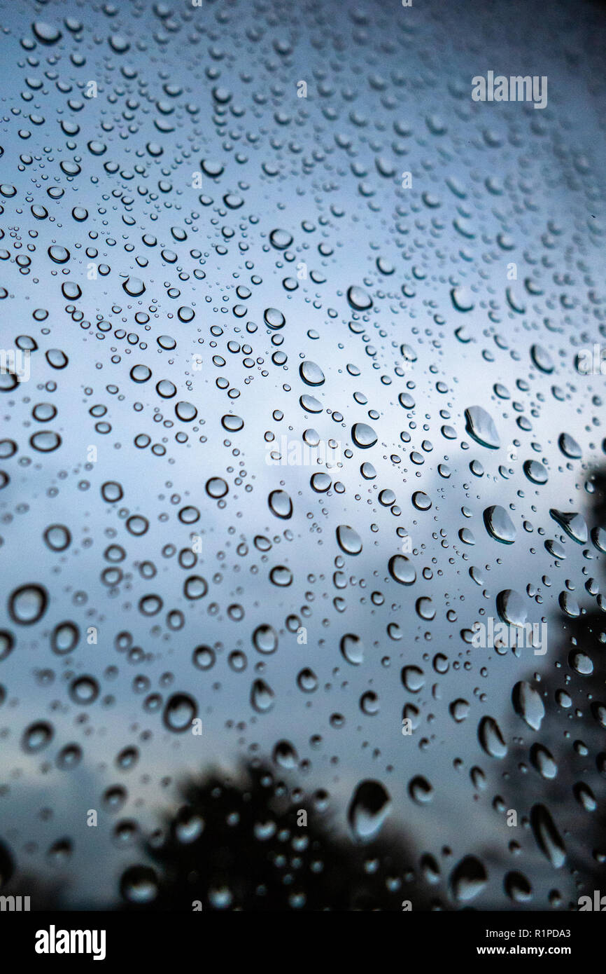 Gouttes de pluie sur fenêtre contre ciel sombre sombre Banque D'Images