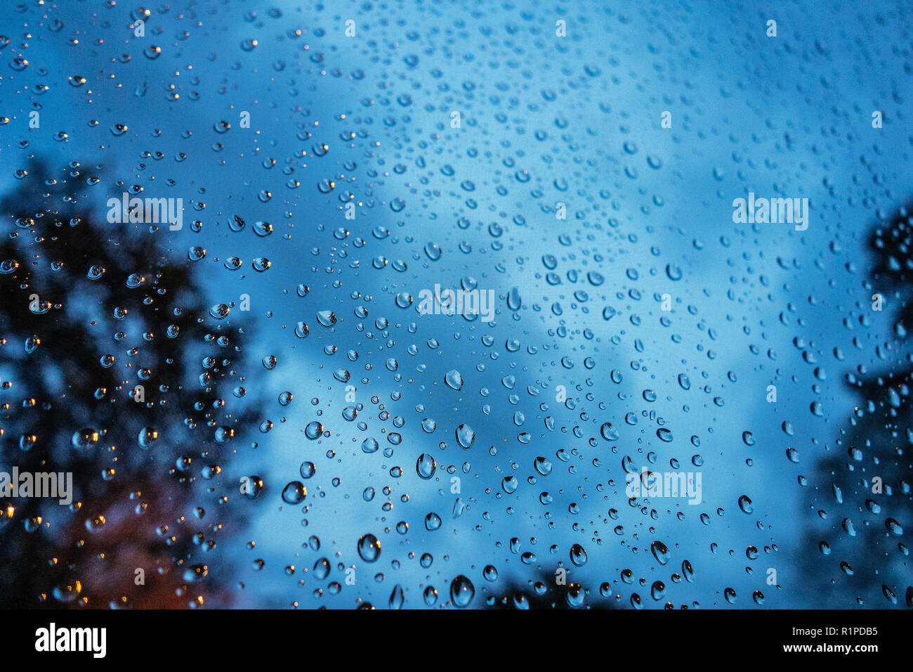 Gros plan très photographie de gouttes de pluie sur la fenêtre en verre avec ciel sombre à l'arrière-plan Banque D'Images