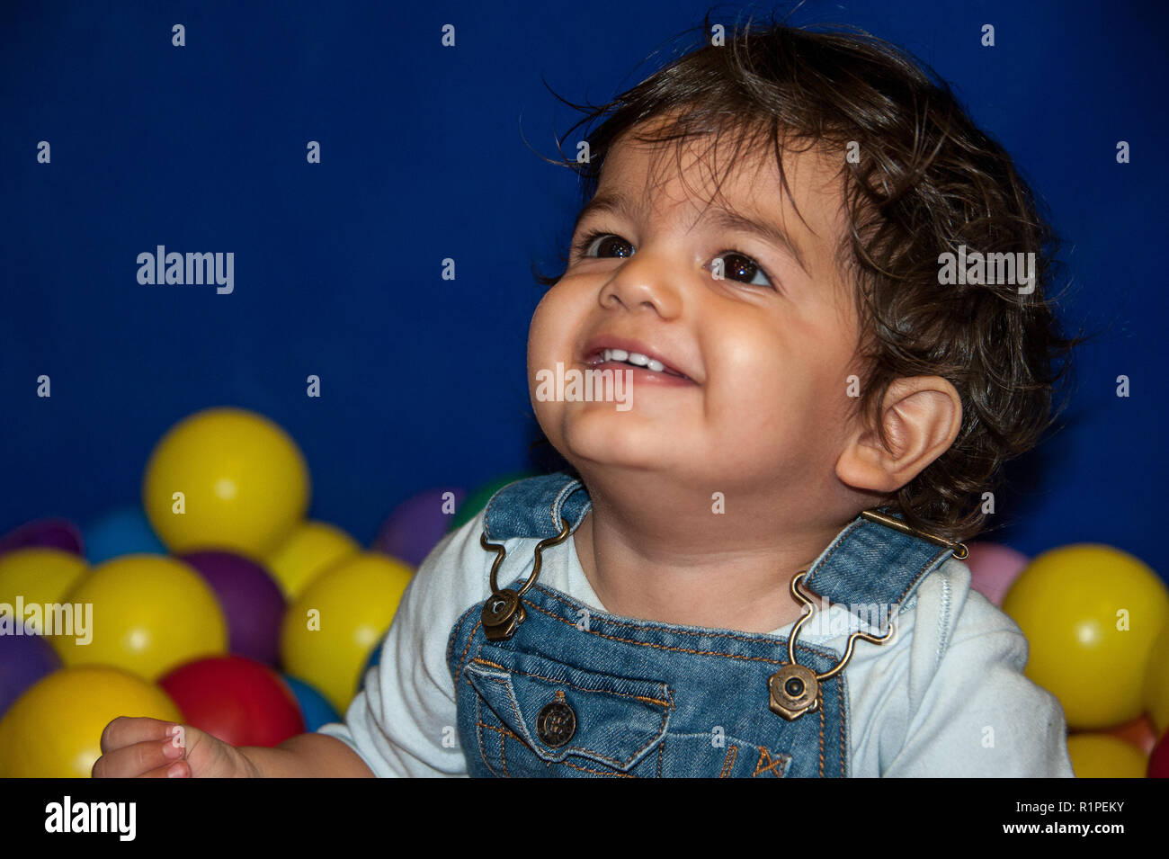 Portrait d'un enfant souriant avec de beaux yeux, assis parmi les boules colorées Banque D'Images