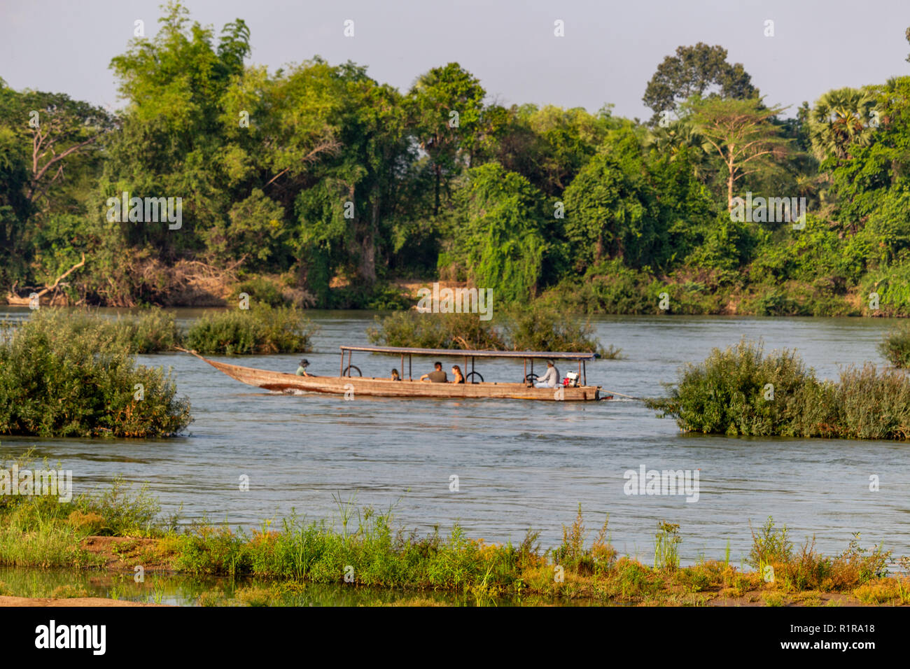 Don Det, Laos - 22 Avril 2018 : bateau naviguant sur le fleuve Mékong est entouré d'une forêt près de la frontière cambodgienne Banque D'Images