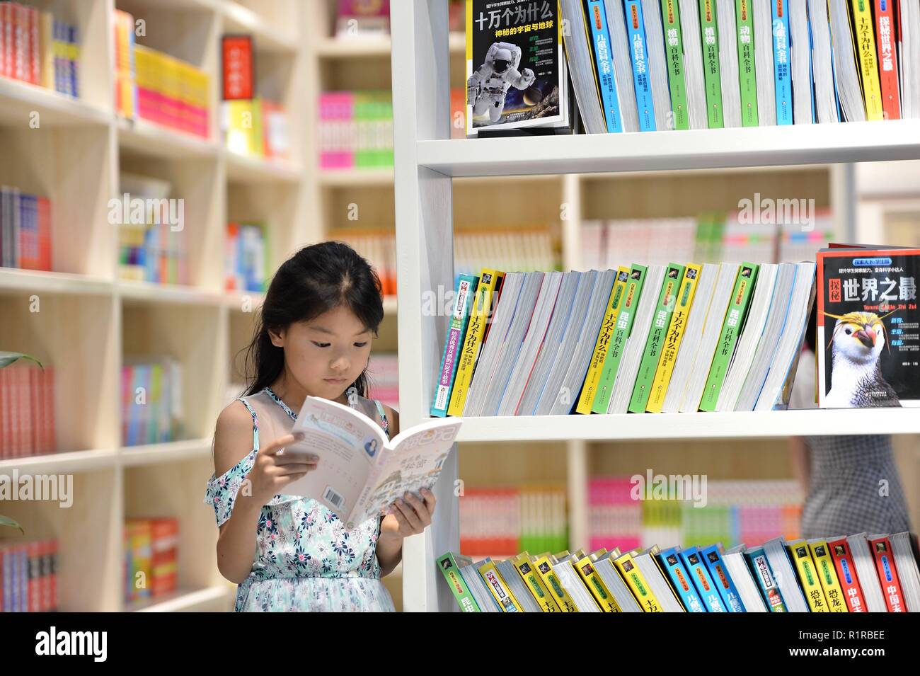 Beijing, Chine. 4 juillet, 2018. Un enfant lit un livre à la librairie Xinhua dans le comté de Baokang de Chine centrale, la province du Hubei, le 4 juillet 2018. Des données de l'Administration de la presse et de publication (NPPA) montre que la Chine a connu une croissance rapide de son industrie de l'édition au cours des quatre dernières décennies, avec le nombre de maisons d'édition, passant de 105 à plus de 580. Les librairies physiques en Chine ont pris le chemin du développement intégré et de la transformation et de la mise à niveau, grâce à des politiques mises en place ces dernières années. Crédit : Yang Tao/Xinhua/Alamy Live News Banque D'Images