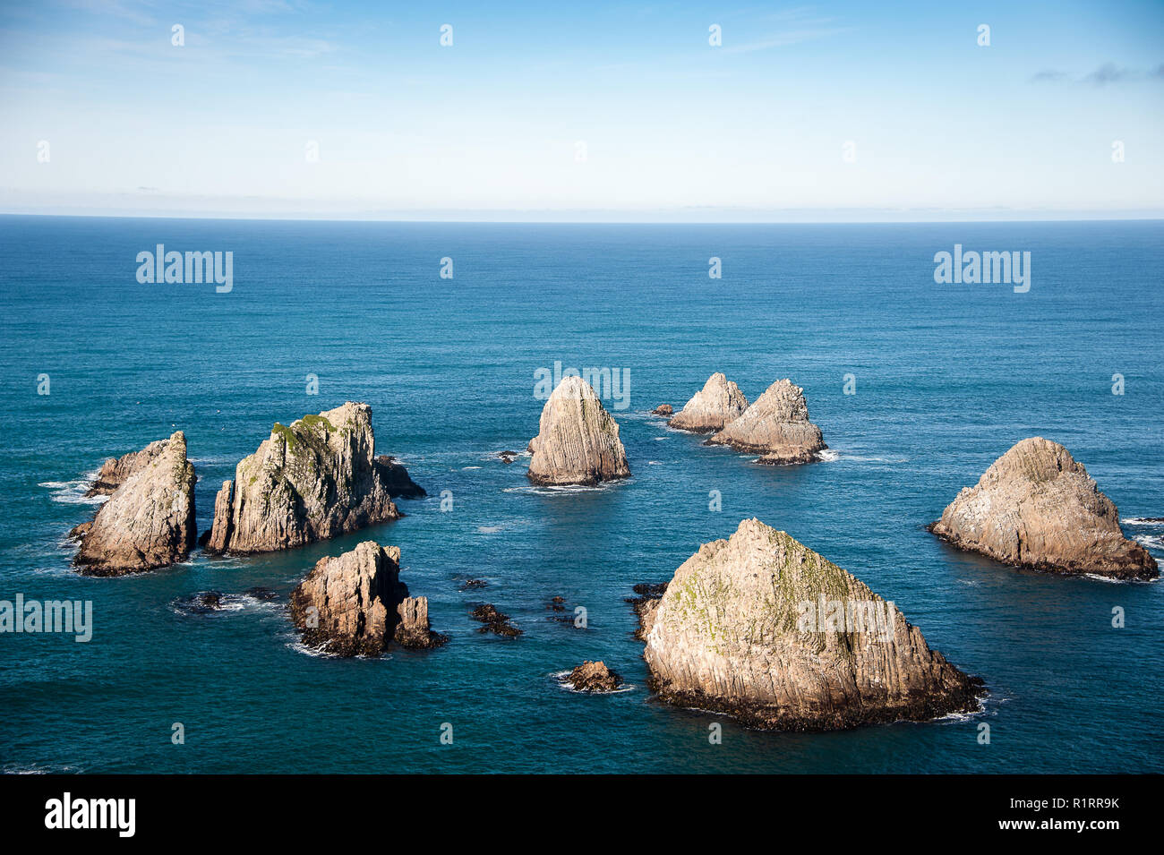 Les Nuggets, reliefs antiques sur la côte Catlins, Nouvelle-Zélande. Cercle d'îlots rocheux dans un océan bleu profond Banque D'Images