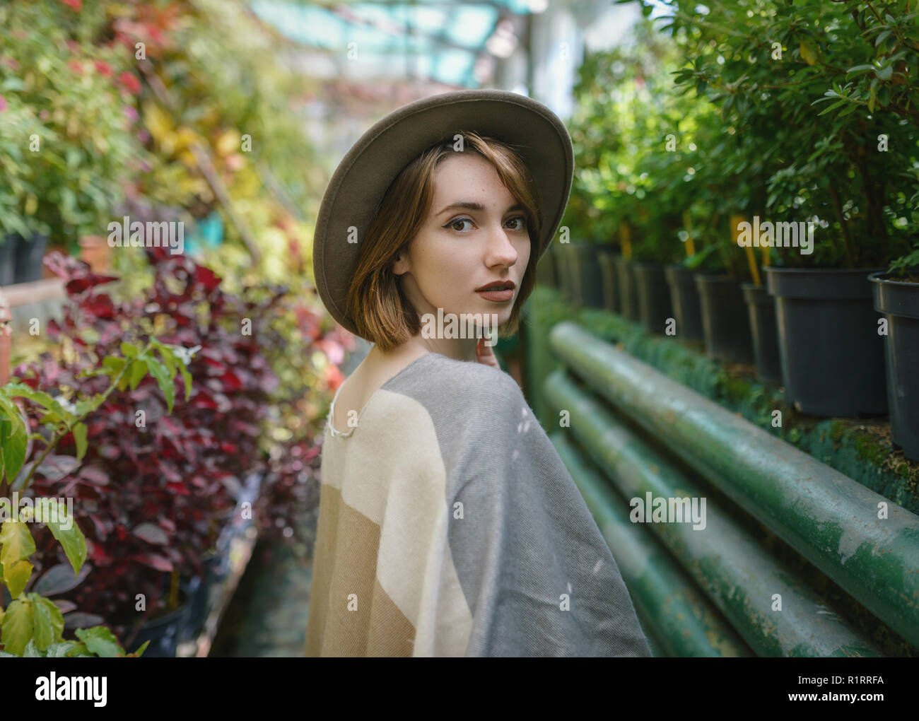 Jeune femme à la mode en portant un chapeau et poncho chez les plantes tropicales. Banque D'Images