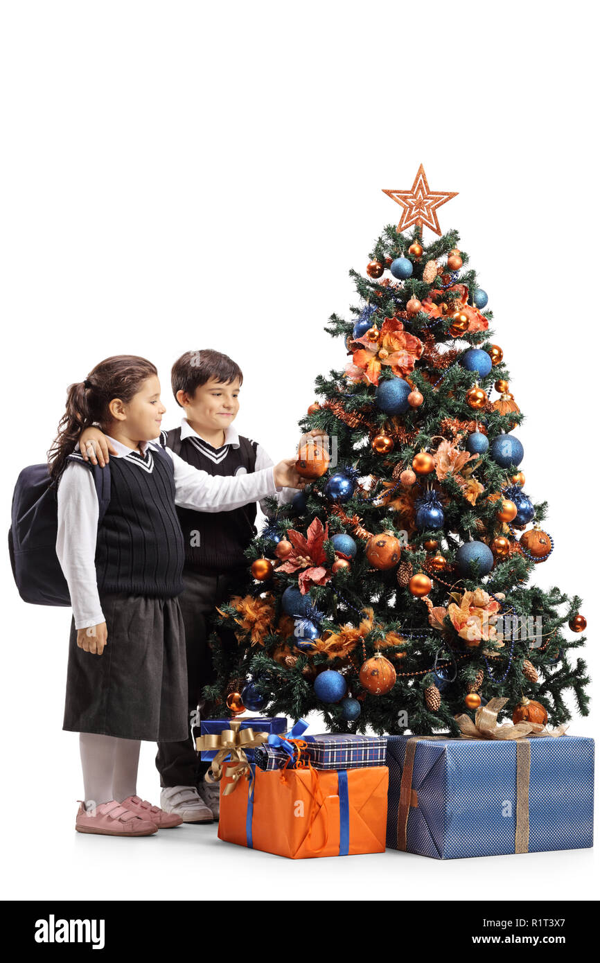 Tourné sur toute la longueur d'une écolière et écolier decorating a Christmas Tree isolé sur fond blanc Banque D'Images