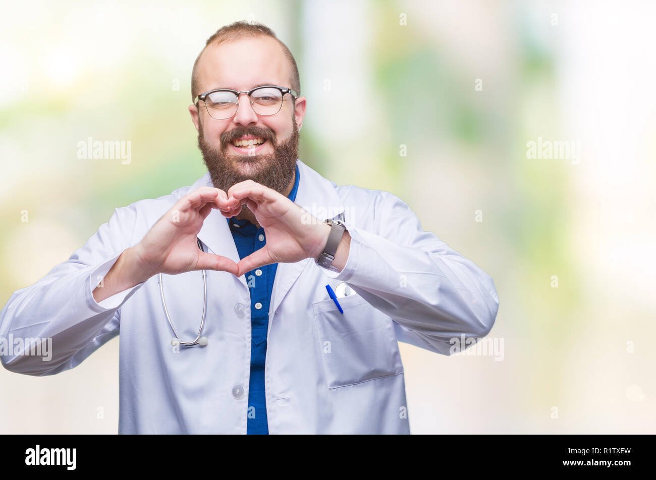 Portrait jeune homme portant la blouse blanche médicale sur fond isolé smiling in love montrant le symbole de coeur et la forme des mains. Con romantique Banque D'Images