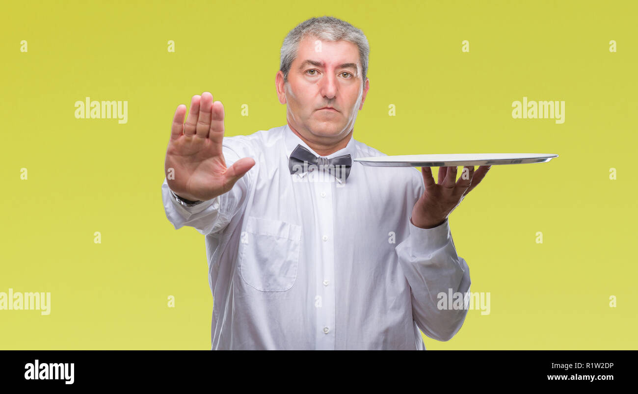 Beau garçon senior man holding silver tray sur fond isolé avec main ouverte faisant stop avec de sérieux et de confiance, la défense de l'expression Banque D'Images