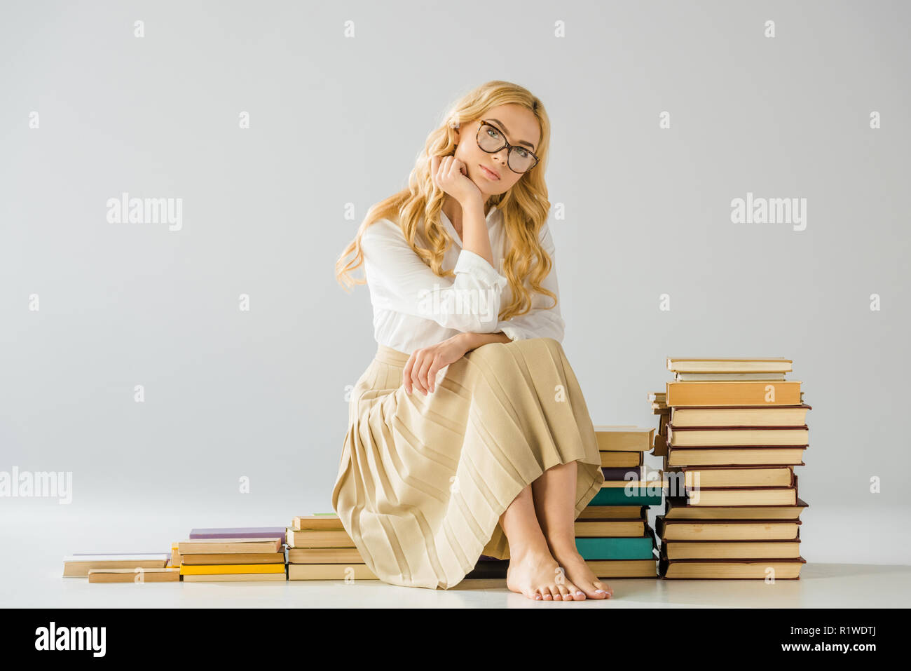 Belle femme nu réfléchie dans les verres assis sur les mesures faites de  livres Photo Stock - Alamy