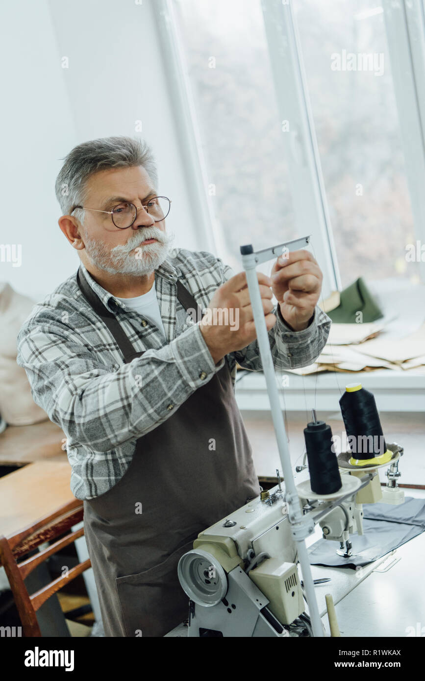 L'accent sur mesure d'âge moyen dans les chaînes de coupe tablier sur machine à coudre à l'atelier Banque D'Images