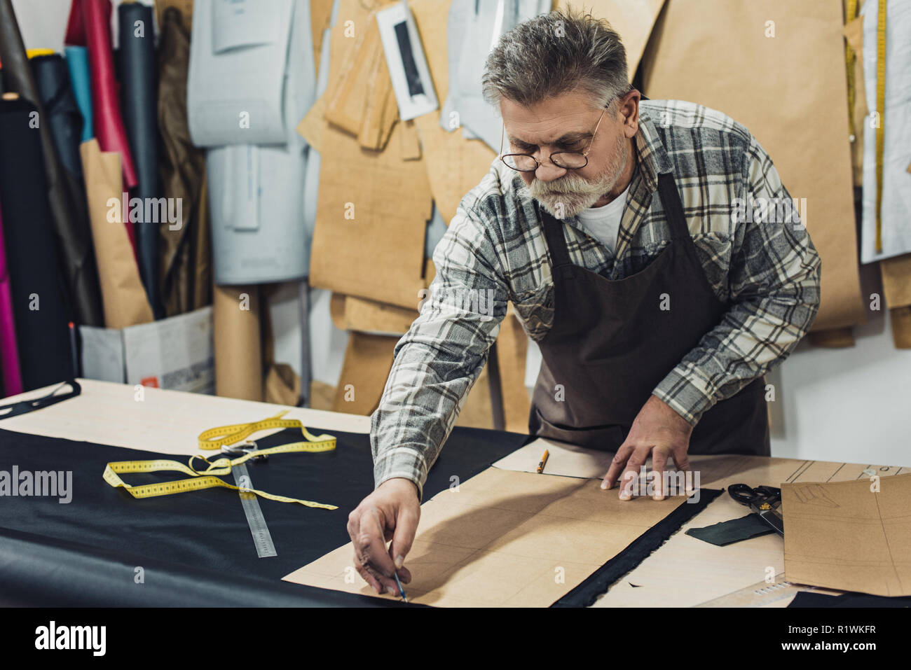 Sac à main en cuir hommes mûrs sérieux artisan en tablier et au studio de travail lunettes Banque D'Images