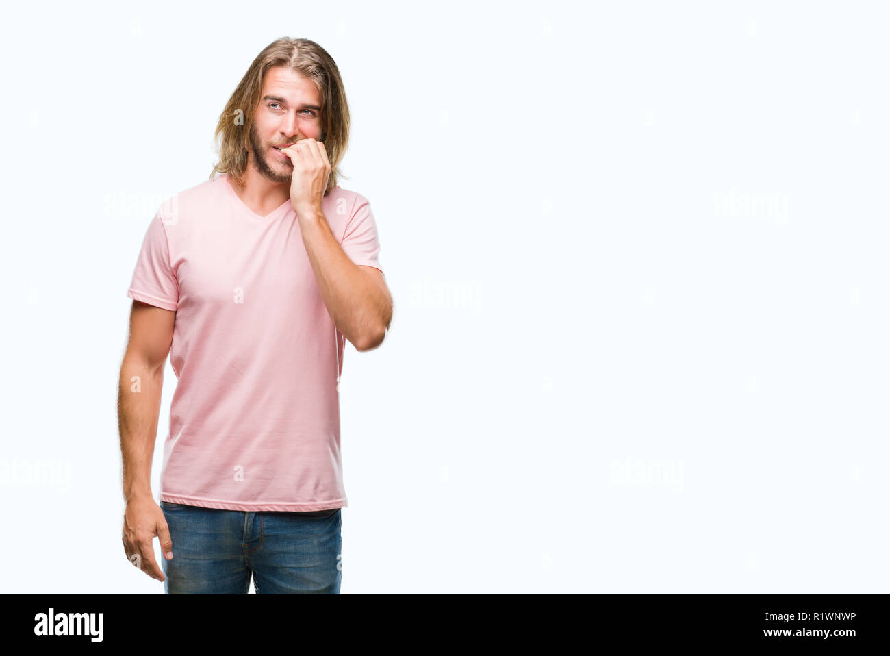 Jeune homme séduisant aux cheveux longs sur fond isolé à souligné et nerveux avec les mains sur la bouche de mordre les ongles. Problème d'anxiété. Banque D'Images