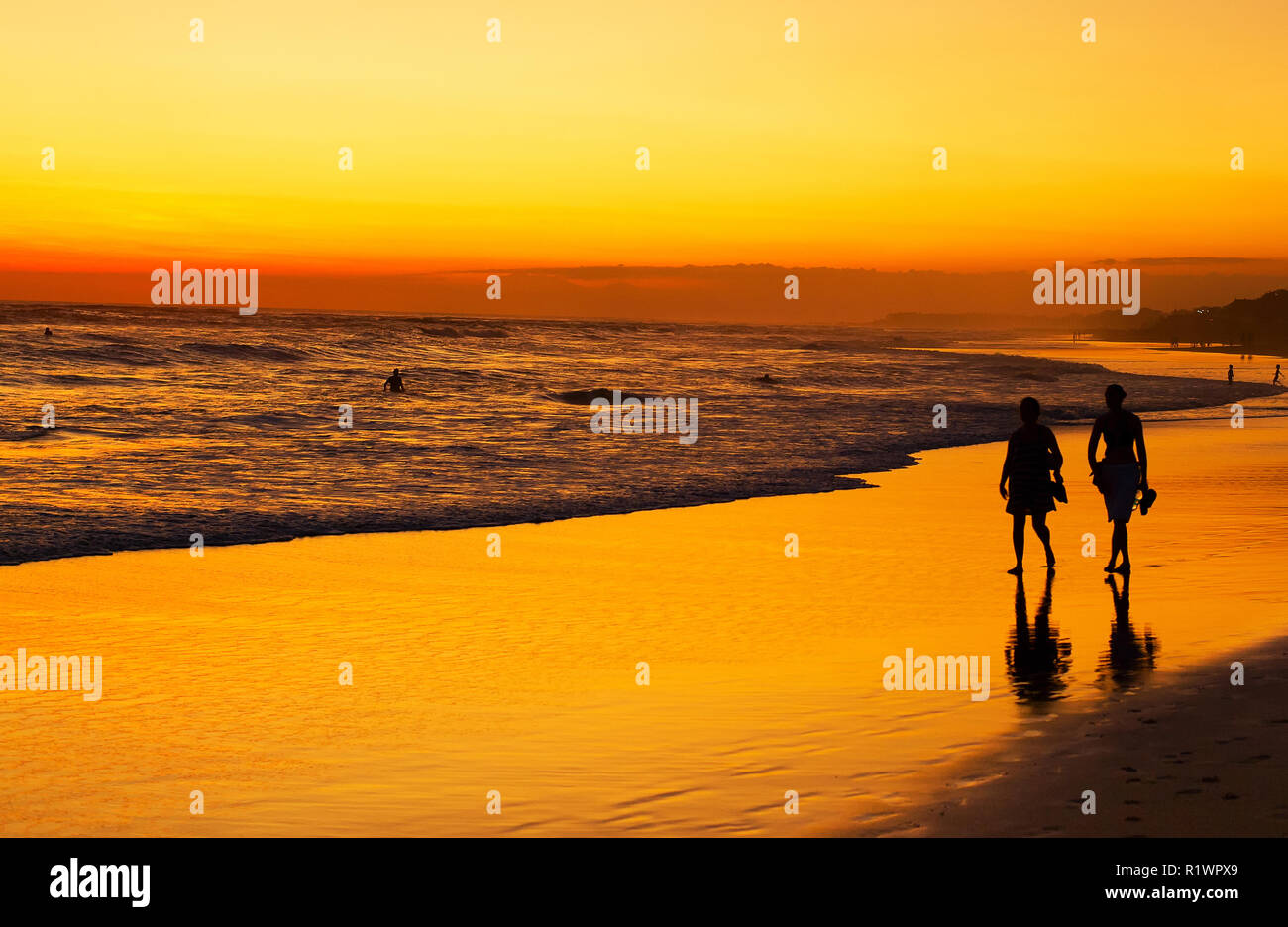 Les gens qui marchent sur la plage sur l'océan au coucher du soleil. L'île de Bali, Indonésie Banque D'Images