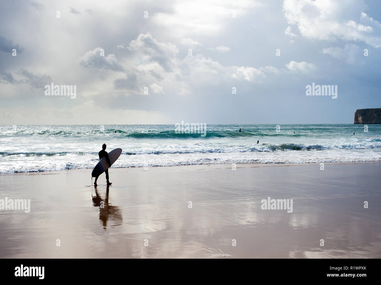 Surf surfer avec la marche sur la plage au coucher du soleil. Algarve, Portugal Banque D'Images