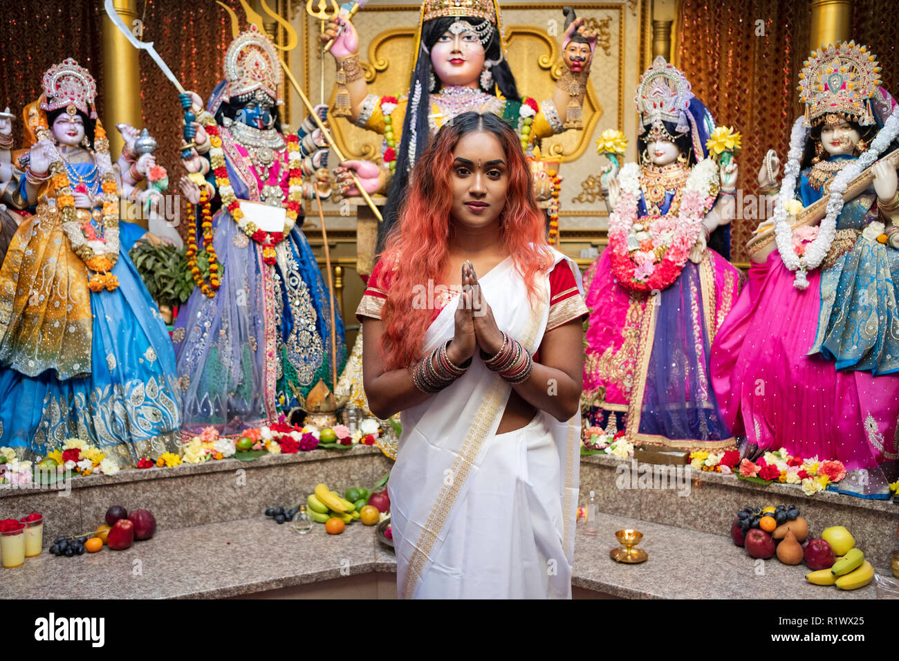 Portrait d'une belle jeune femme hindoue en face des statues de divinités dans un temple dans le Queens, New York. Banque D'Images