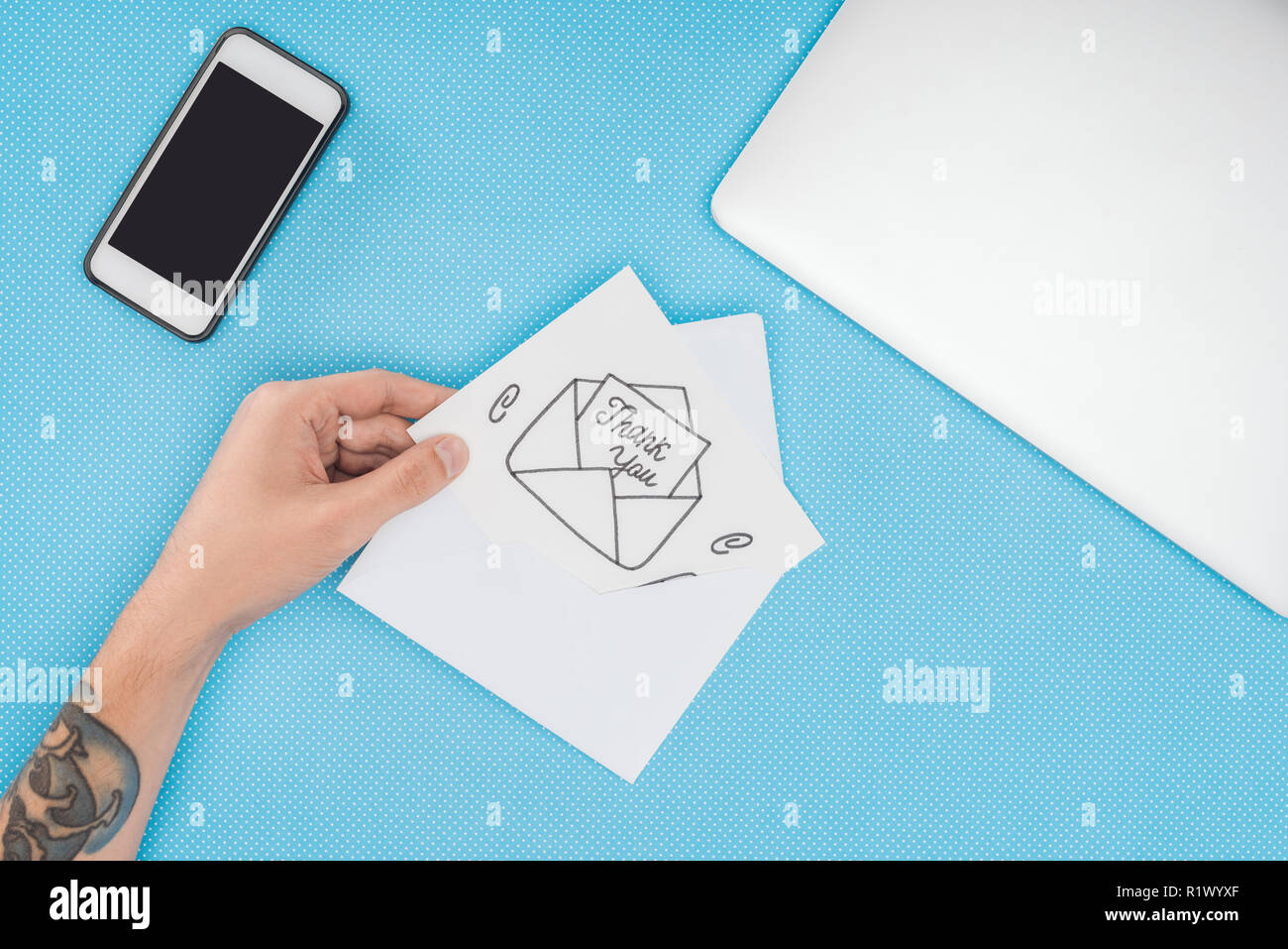 Personne cultivée holding white card avec lettrage merci sortant de l'enveloppe à la main et smartphone isolé sur fond bleu Banque D'Images