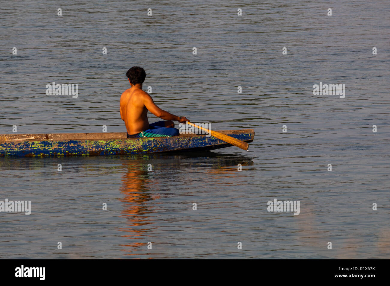 Don Det, Laos - 22 Avril 2018 : un homme en bois local aviron long boat sur le Mékong au sud du Laos Banque D'Images