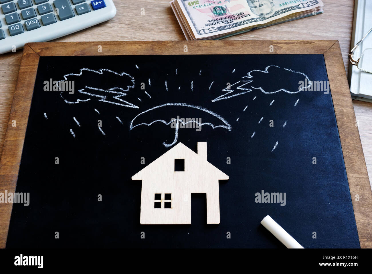 Assurance de biens. Tableau noir avec des nuages et le modèle de maison. Banque D'Images