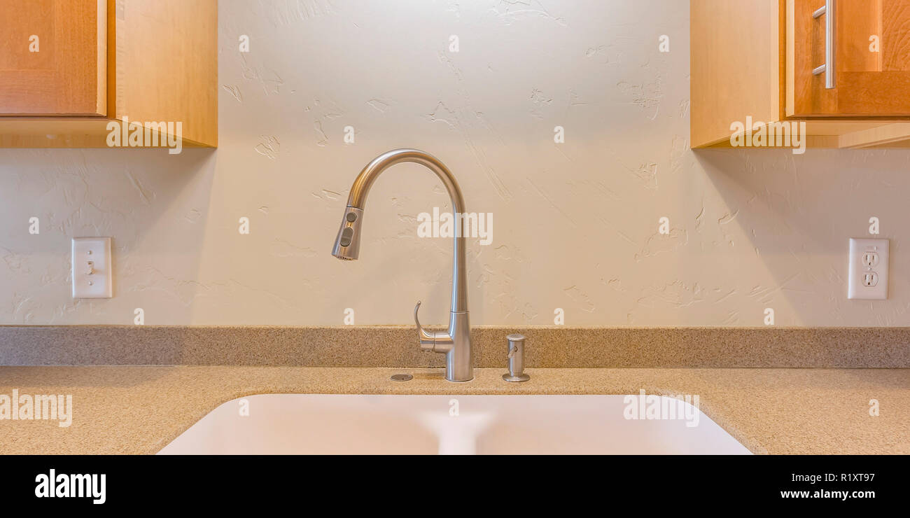 Robinet et évier contre mur blanc avec les armoires Banque D'Images