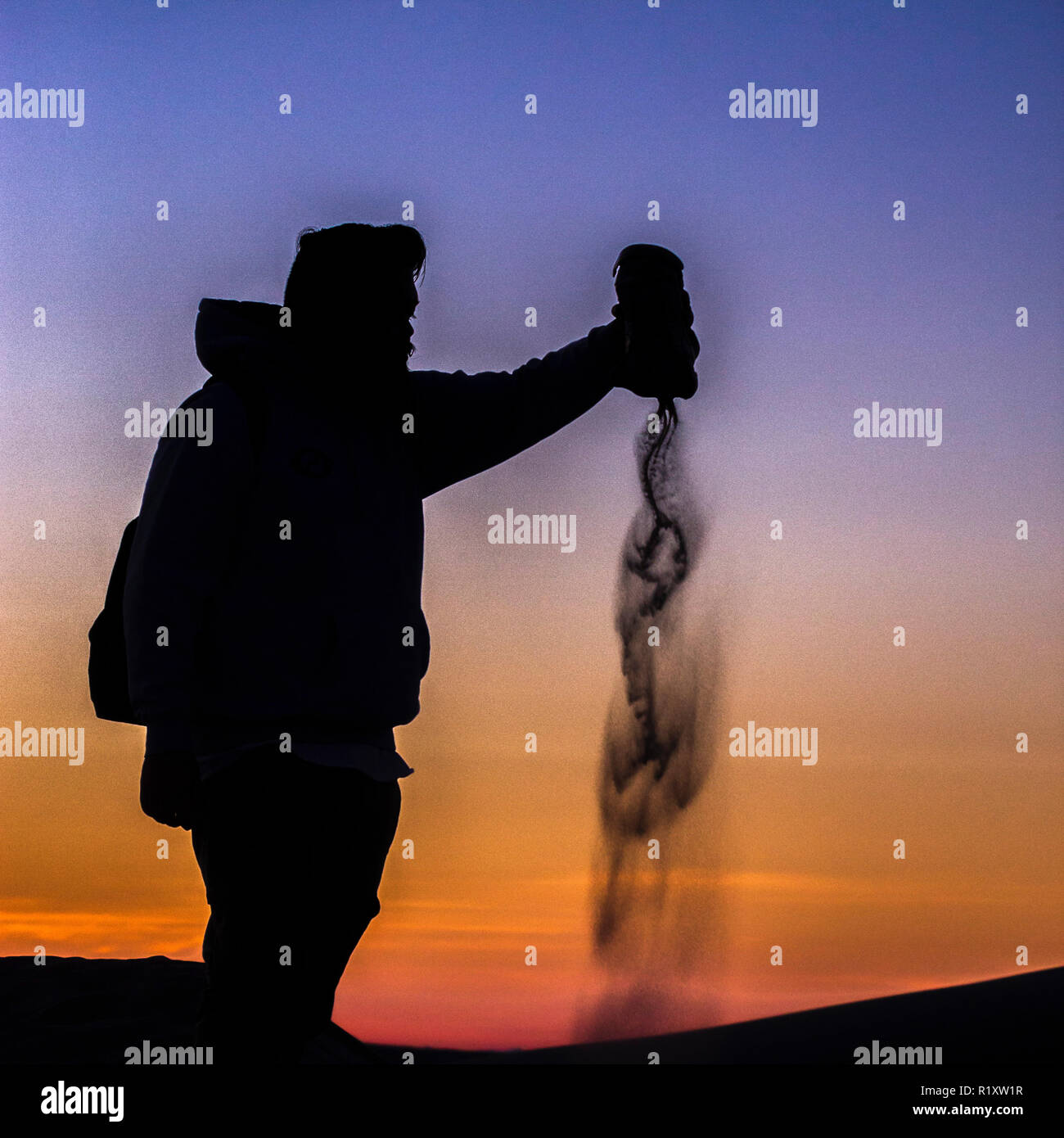 Man pouring sable par les dunes de sable au coucher du soleil en CA Banque D'Images