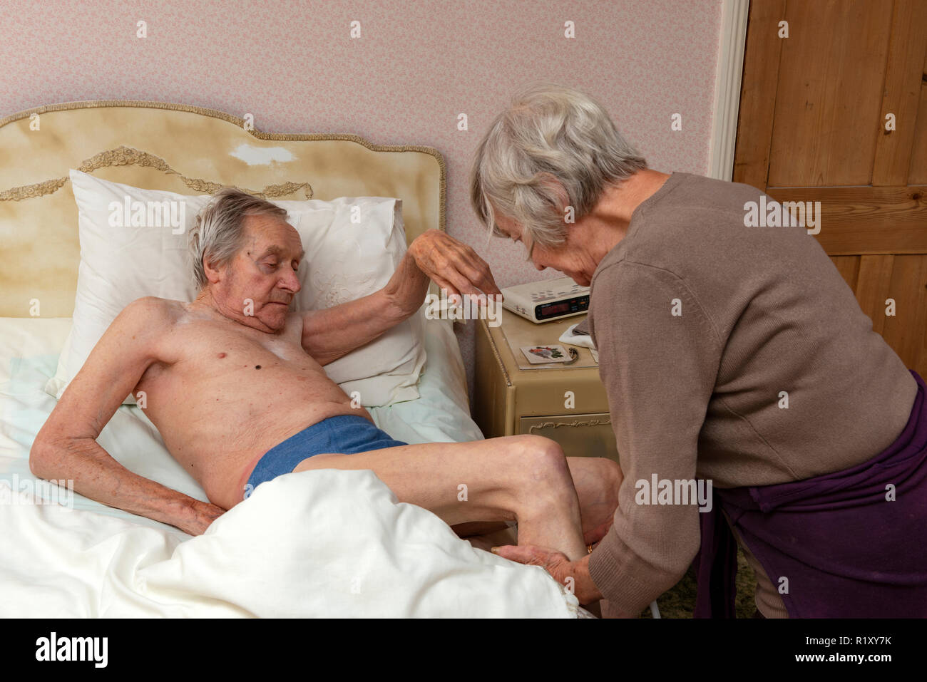 Un homme âgé de l'aide pour sortir du lit par sa sœur Banque D'Images