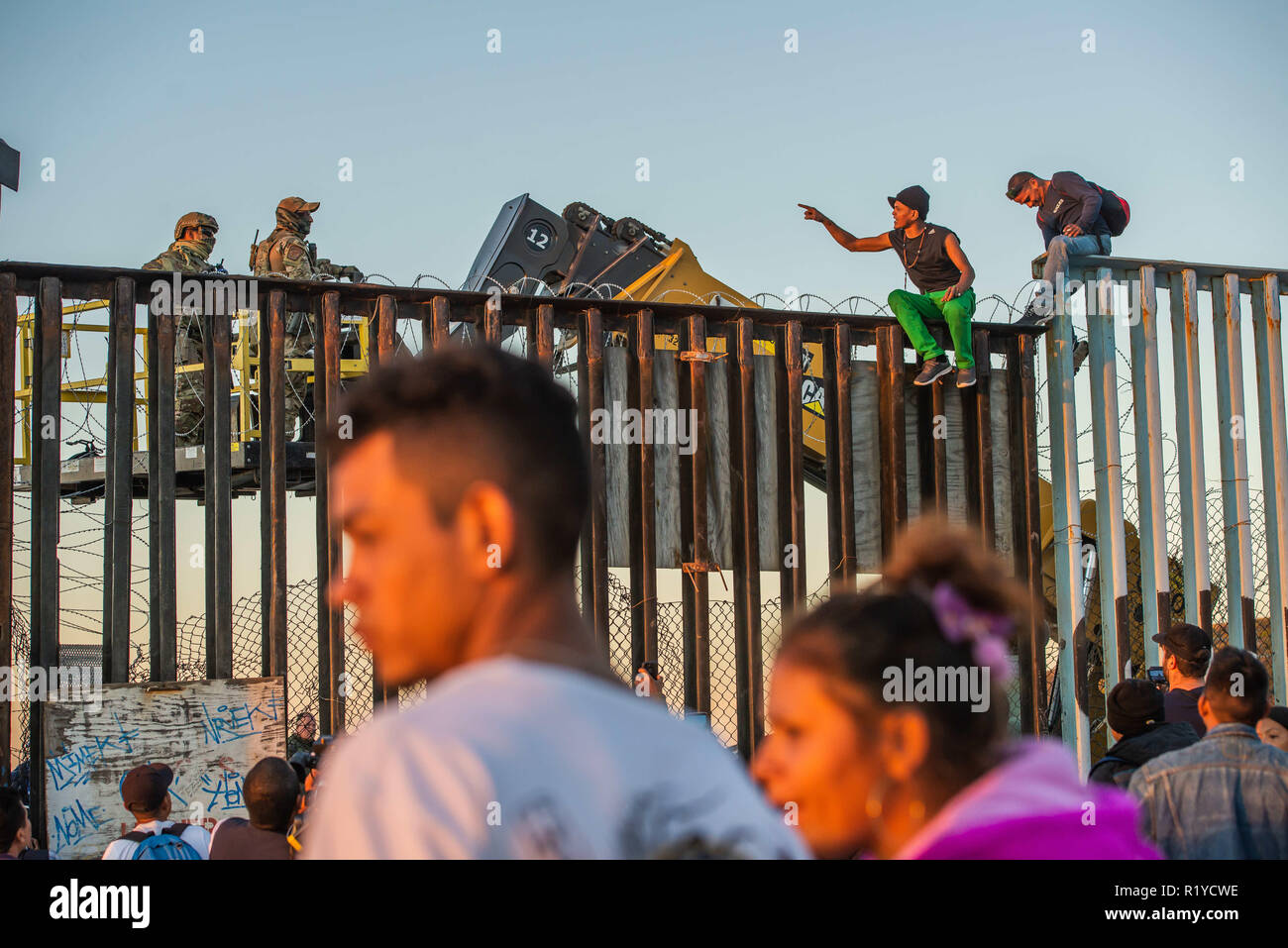 Tijuana, au Mexique. 14Th Nov, 2018. Les demandeurs d'asile de l'Amérique centrale, alias le 'Migrant' Caravane, converse avec US Border Patrol au sommet de la frontière La frontière entre les États-Unis et le Mexique à Tijuana. Les chariots élévateurs sont là pour modifier la frontière pour ajouter plus de barbelé au sommet de la clôture. Credit : Vito Di Stefano/ZUMA/Alamy Fil Live News Banque D'Images