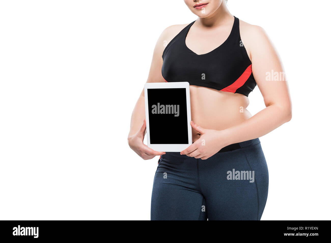 Cropped shot of young woman in sportswear surpoids holding digital tablet isolated on white Banque D'Images