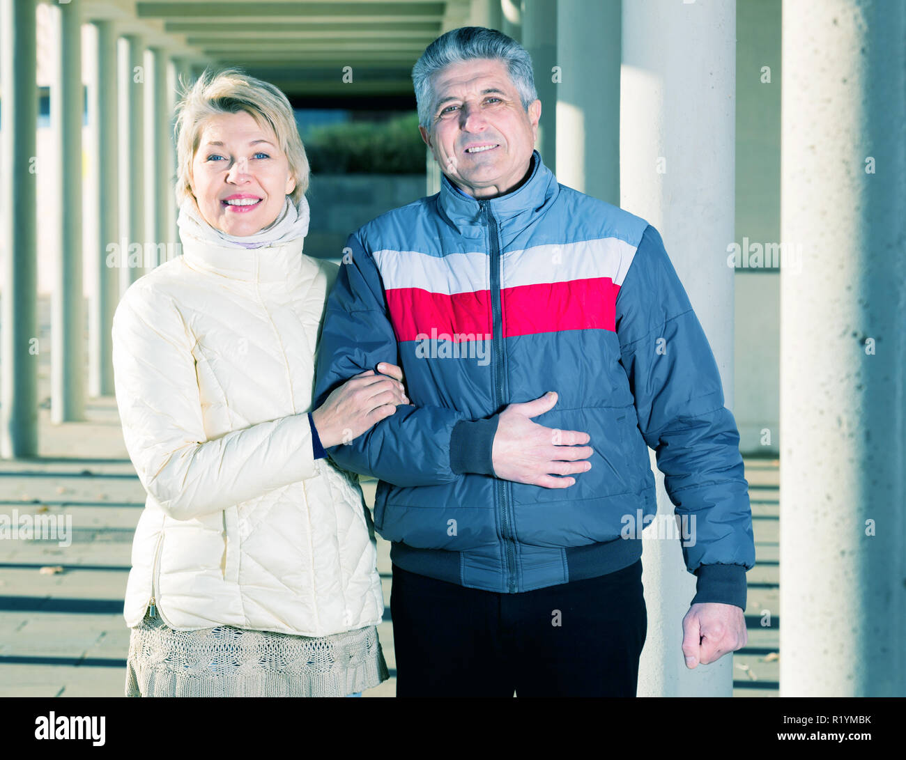 Cheerful couple marié va pour marcher entre les piliers en béton sur sunny day Banque D'Images