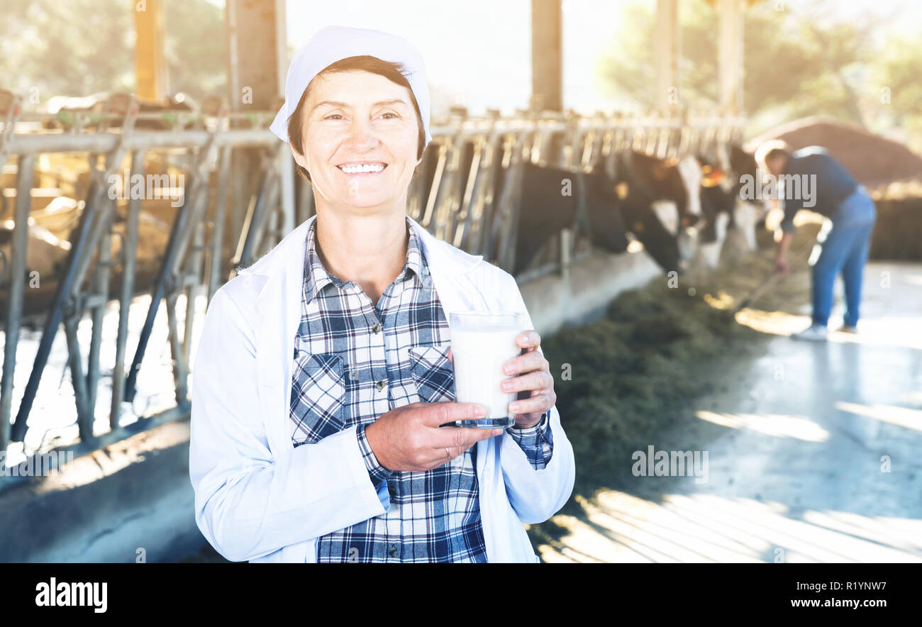 Portrait of smiling woman vétérinaire manteau blanc avec du lait de vache à l'étable de ferme laitière Banque D'Images Portrait of smiling woman vétérinaire manteau blanc avec du lait de vache à l'étable de ferme laitière Banque D'Images