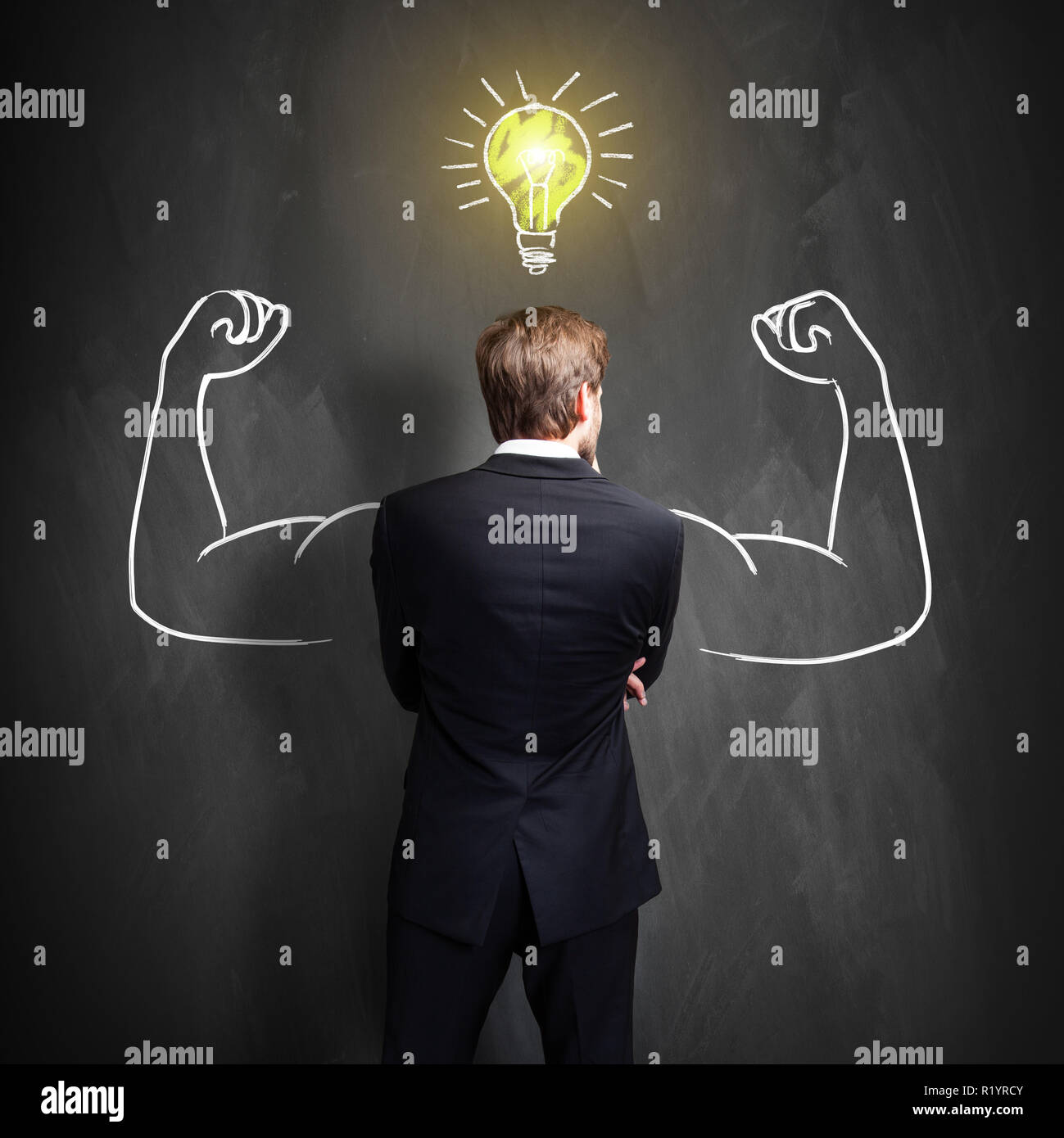 Homme debout devant un tableau avec une ampoule, symbole ayant tiré une idée Banque D'Images