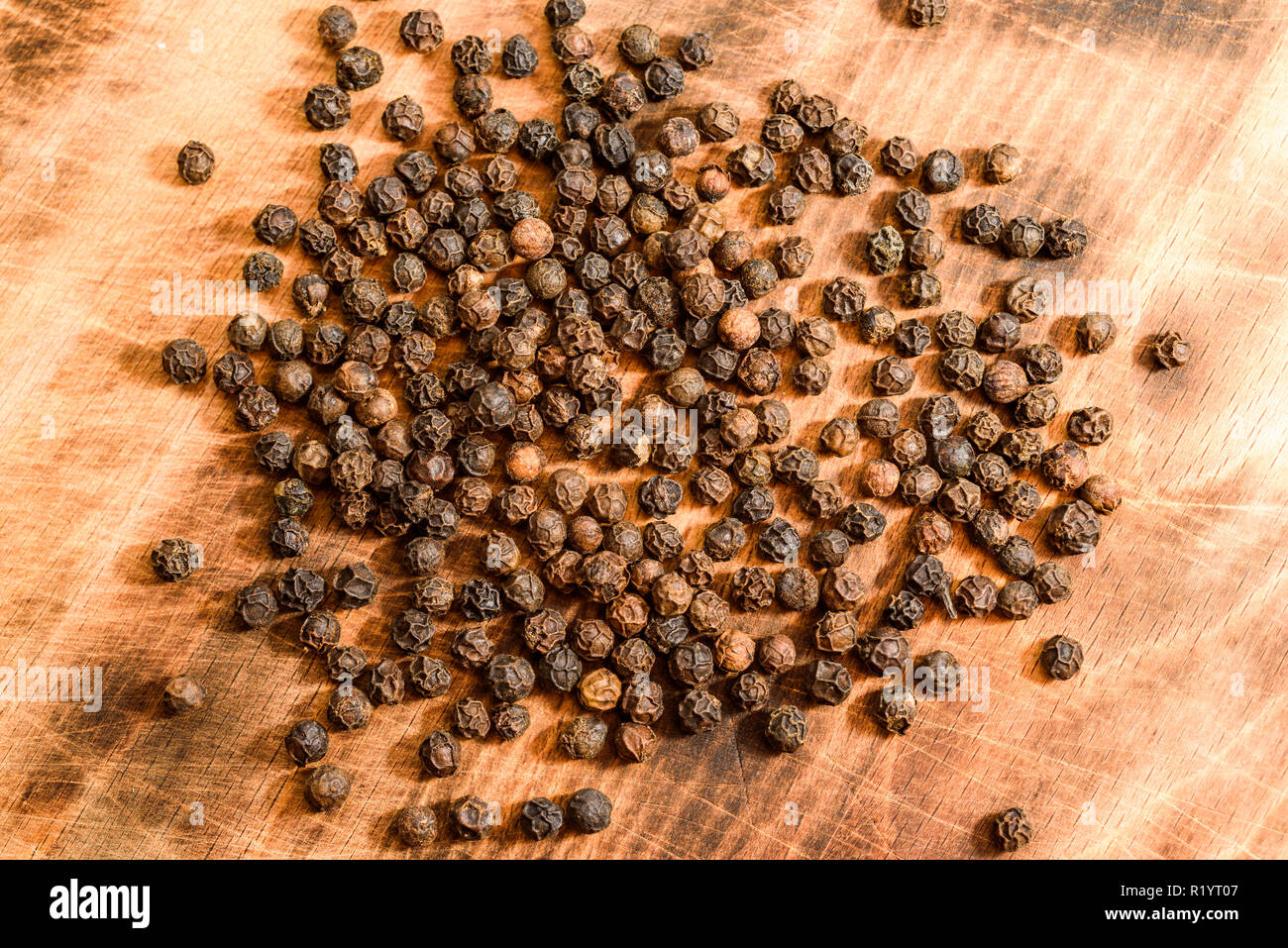 Poivre Noir de Tellicherry sur une planche à découper en bois. Banque D'Images