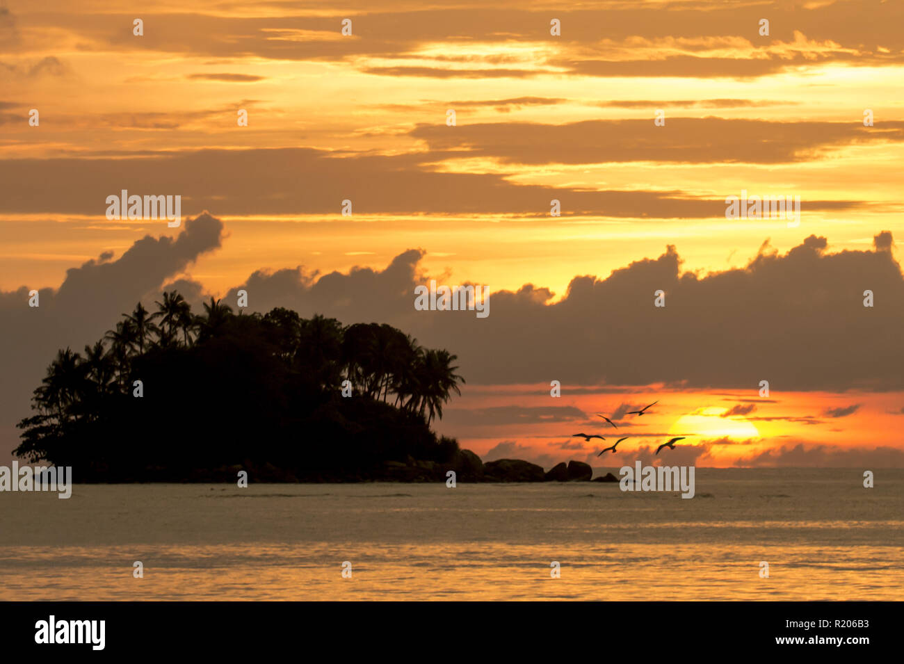 Incroyable coucher du soleil derrière une petite île, vu de la plage de Naiyang à Phuket, Thaïlande Banque D'Images