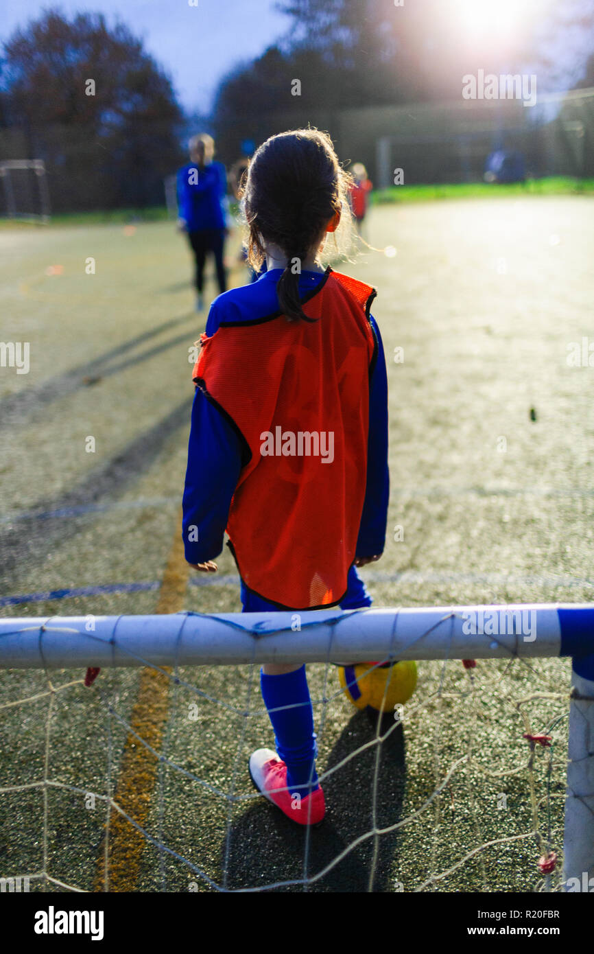Jeune fille jouant au football sur terrain de nuit Banque D'Images