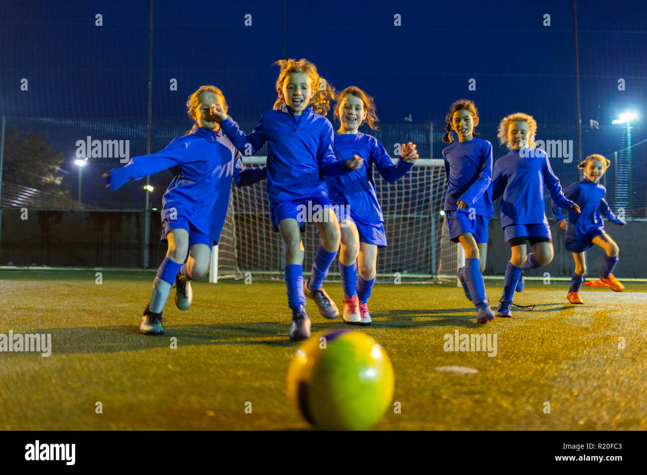 L'équipe féminine de soccer jouer, courir vers la balle sur domaine de nuit Banque D'Images