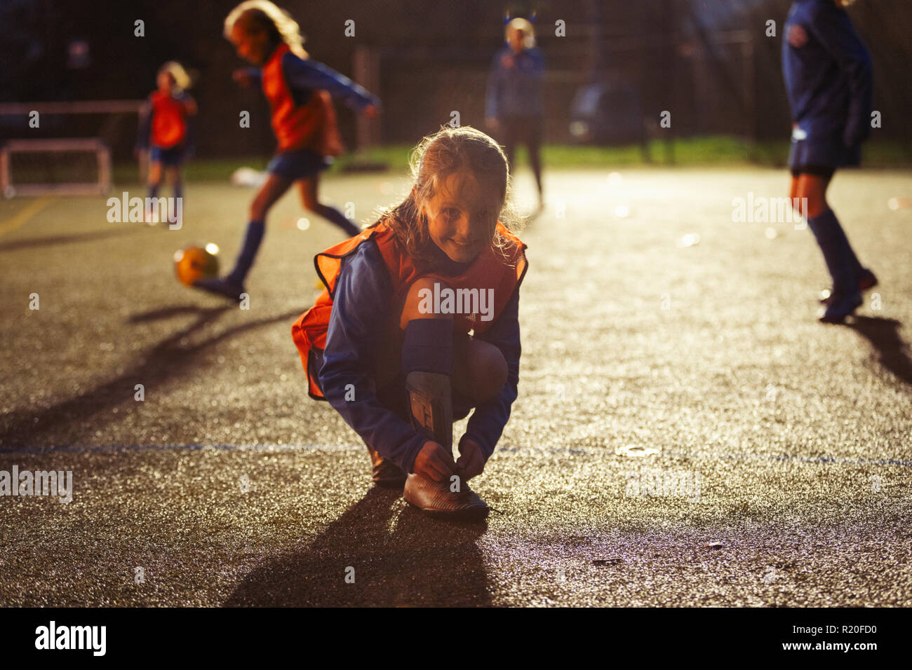 Portrait of smiling girl soccer player attacher ses chaussures sur terrain de nuit Banque D'Images