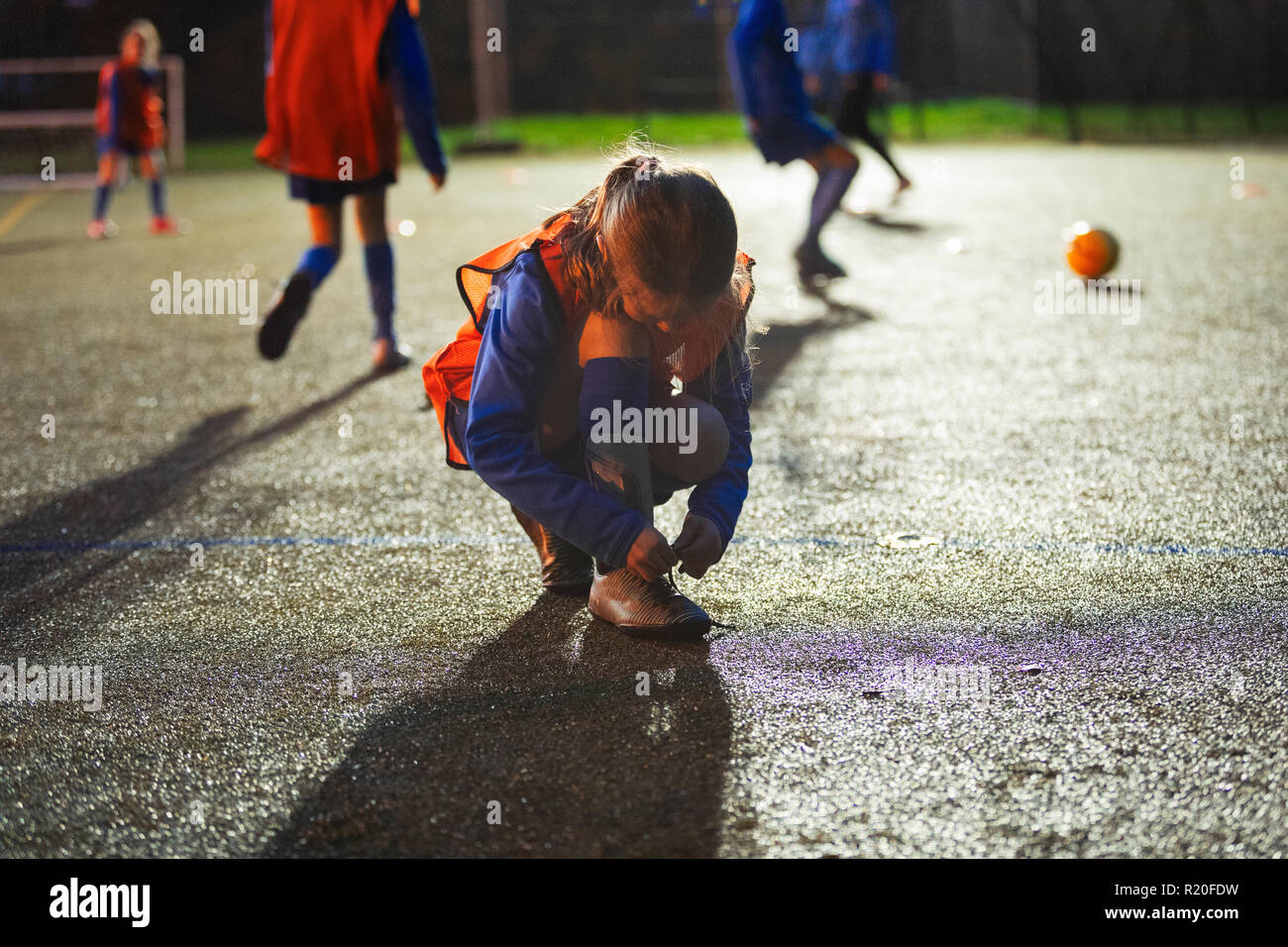 Le joueur de soccer fille chaussure de liage sur terrain de nuit Banque D'Images