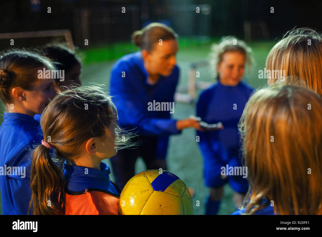 Les joueurs de soccer Girl listening to coach dans huddle Banque D'Images