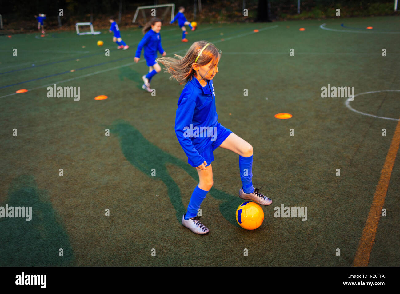 Soccer Girl practicing percer sur terrain de nuit Banque D'Images