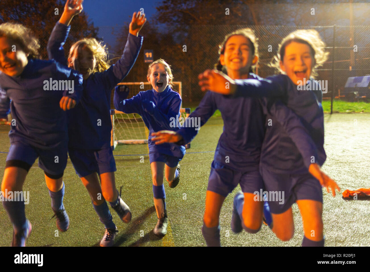 L'équipe de soccer des filles enthousiastes d'exécution et la célébration de la nuit sur le terrain Banque D'Images