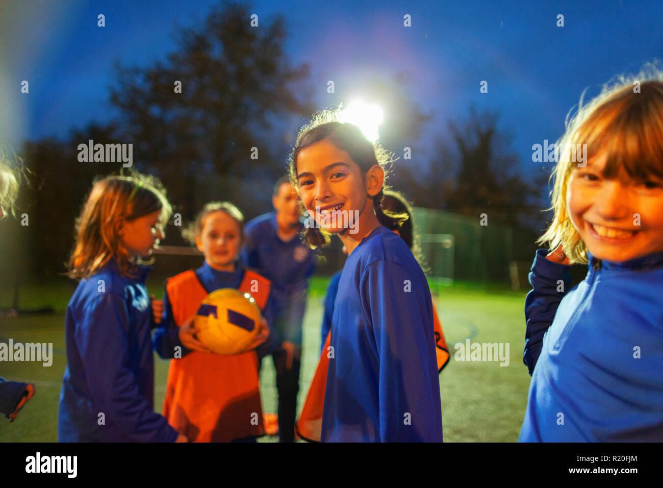 Portrait smiling girls soccer team sur terrain de nuit Banque D'Images