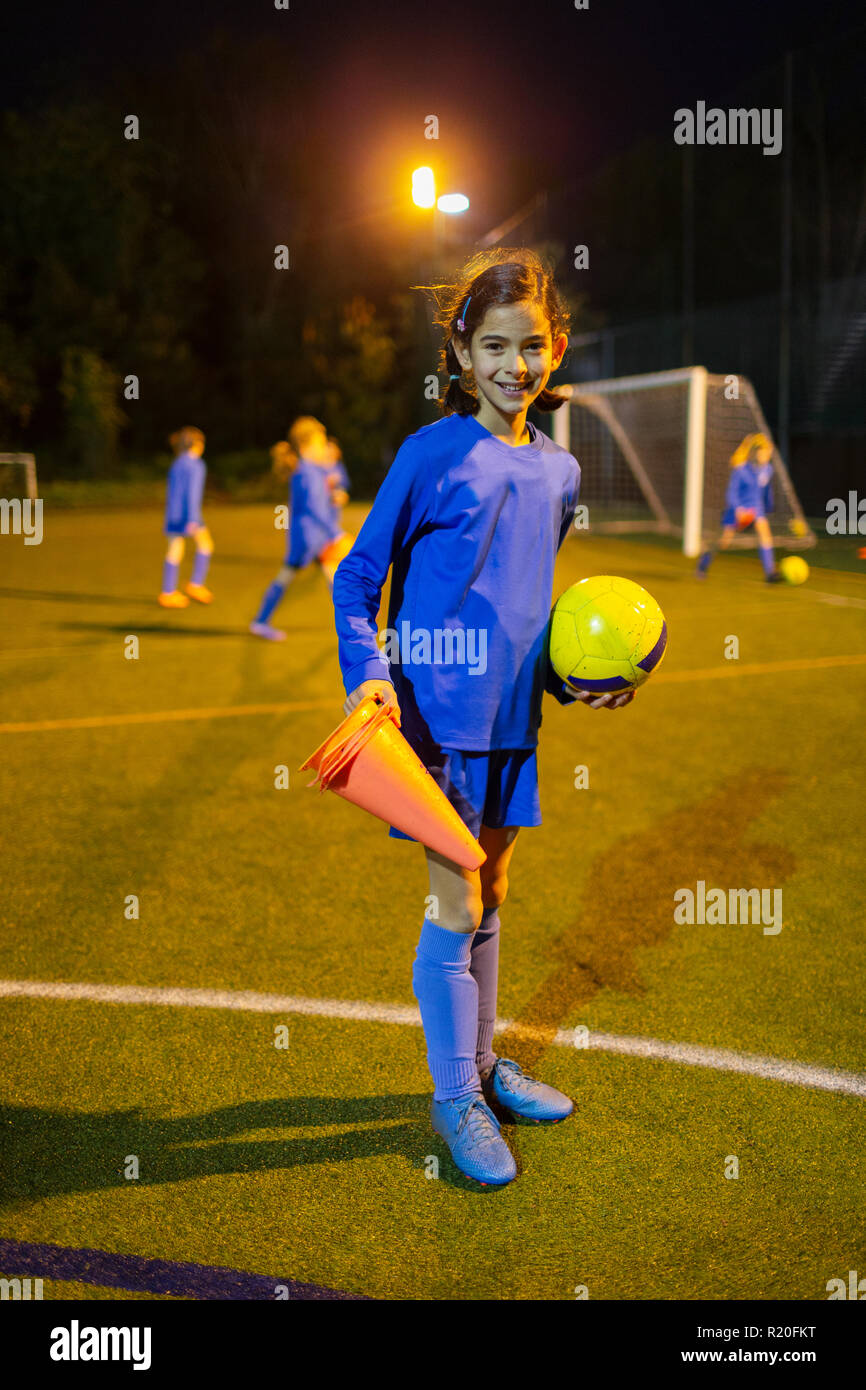 Portrait confiant girl joueur de football sur terrain de nuit Banque D'Images