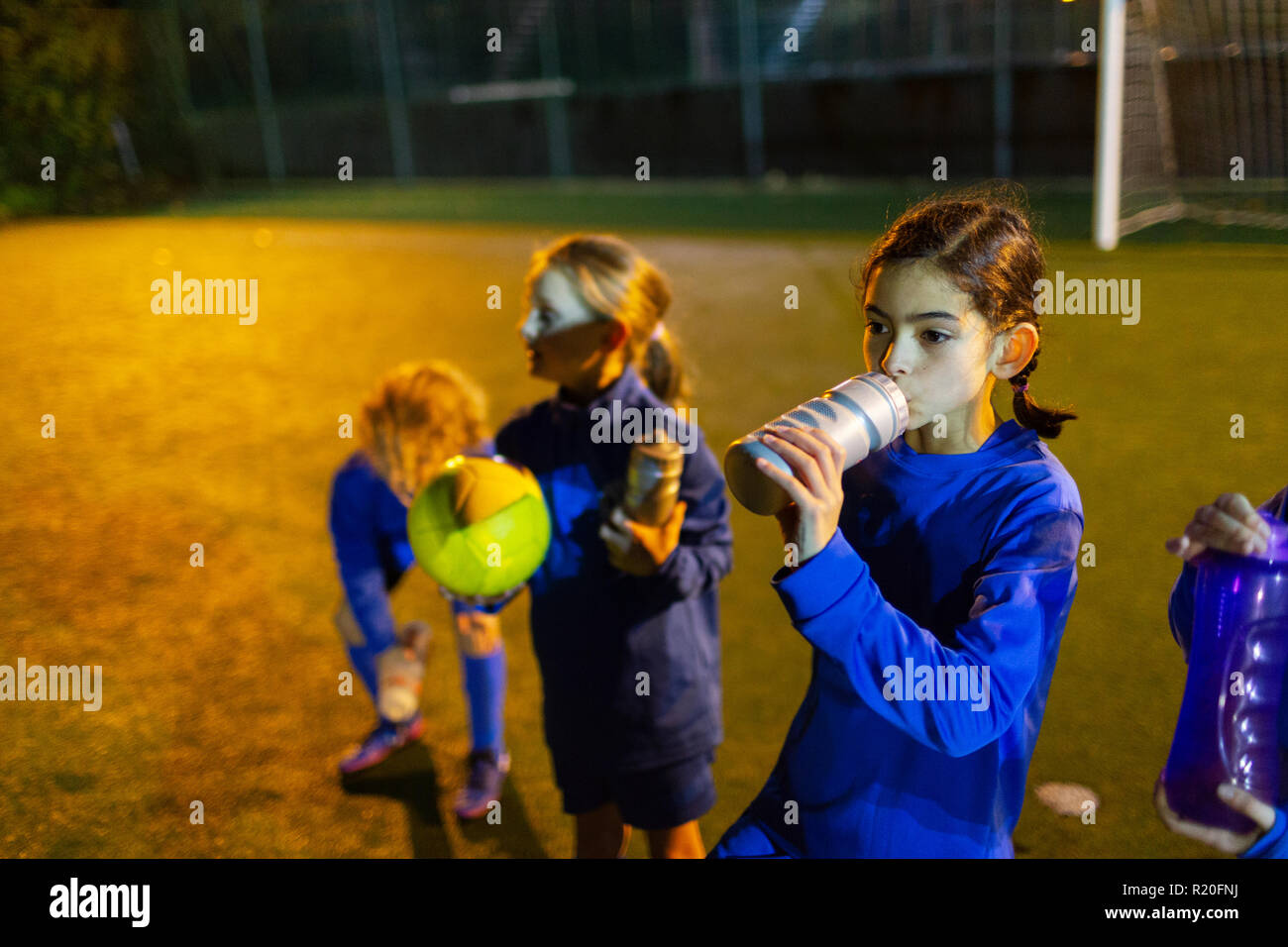 Girl soccer player en faisant une pause sur l'eau potable, domaine la nuit Banque D'Images