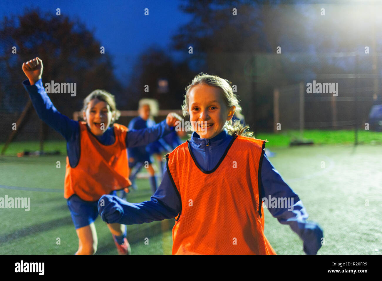 Portrait jeune fille enthousiaste acclamant les joueurs de soccer field at night Banque D'Images
