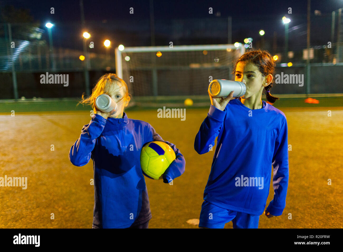 Les joueurs de soccer Girl Taking a break, l'eau potable sur la nuit sur le terrain Banque D'Images