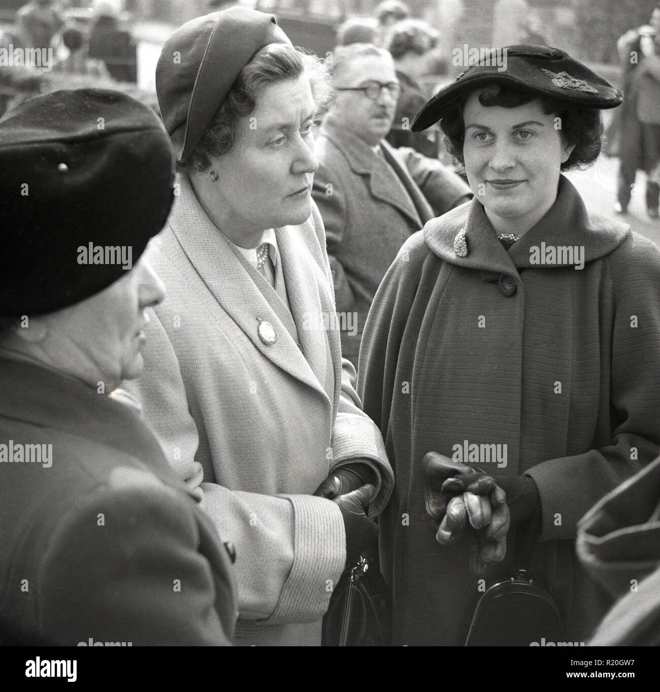Années 1950, trois femmes vêtus de manteaux et chapeaux se tenant ensemble  à l'extérieur à un mariage, England, UK Photo Stock - Alamy