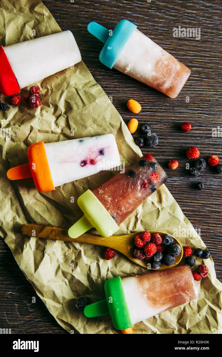 Mise à plat d'afficher beaucoup d'accueil fait un réfrigérateur smoothie jus congelé yaourt glaces avec les baies sauvages sur fond de bois sombre des. Collation santé c Banque D'Images