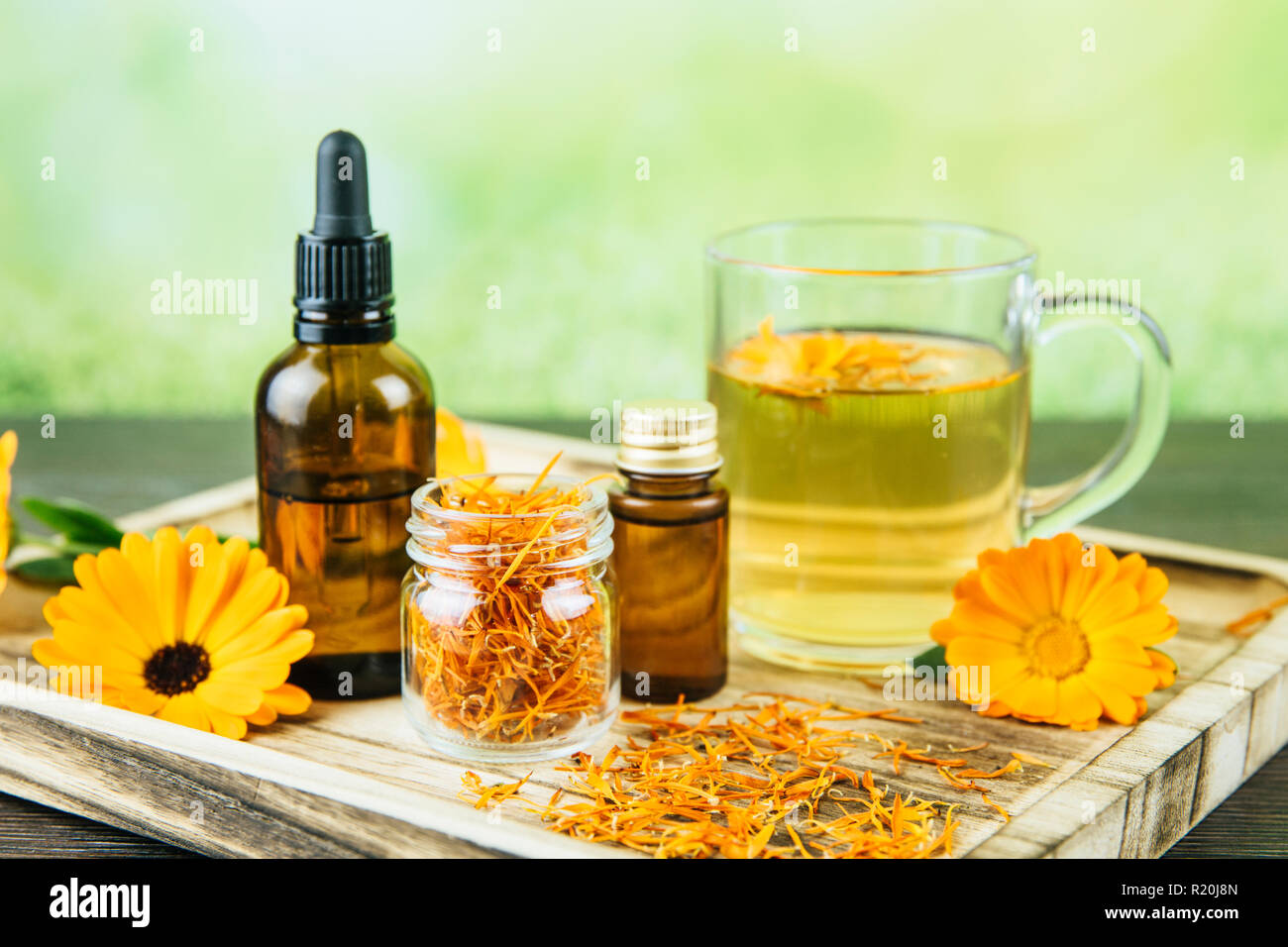 Calendula officinalis, le souci officinal, ruddles, marigold commun ou Scotch marigold différents produits de santé sur le plateau en bois, huile essentielle, teinture Banque D'Images